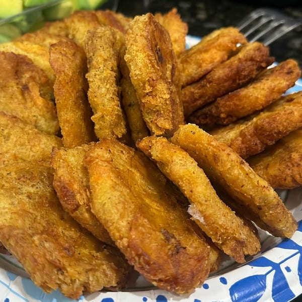 Plate piled with assorted golden-brown fried pastries and savory snacks on a blue-and-white patterned dish.