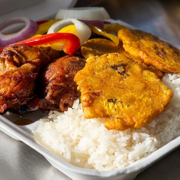 Takeout tray with grilled chicken, fried plantains, white rice, and sliced red peppers and onions.